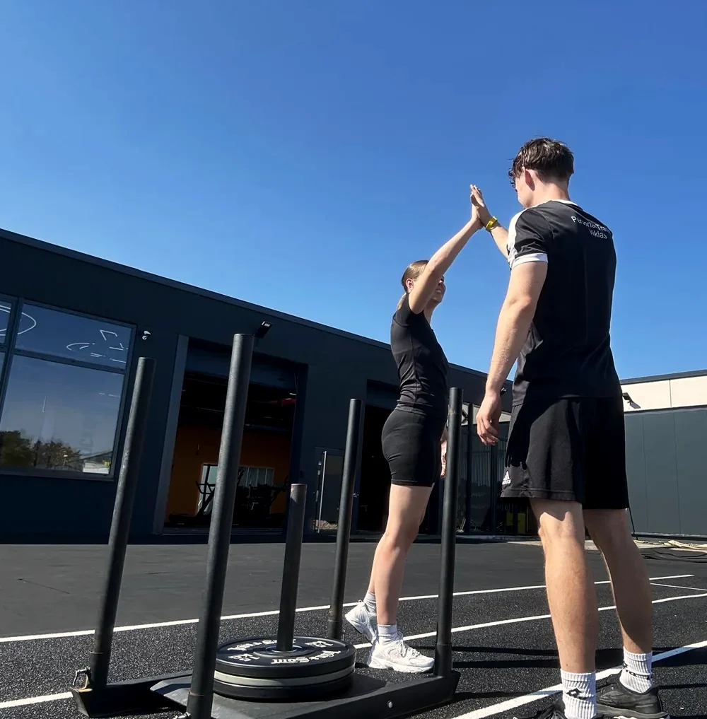 Niklas Donner klatscht nach einer Trainingseinheit mit einer Kundin auf der Hyrox-Fl&auml;che ab